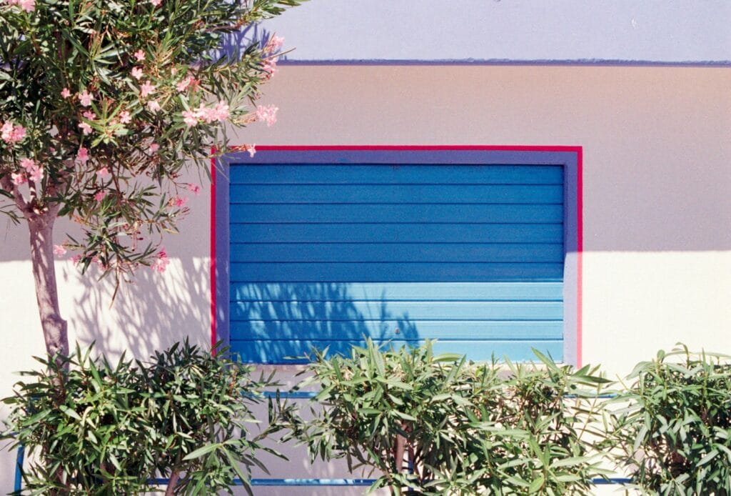 Blue shuttered window with pink flowering tree